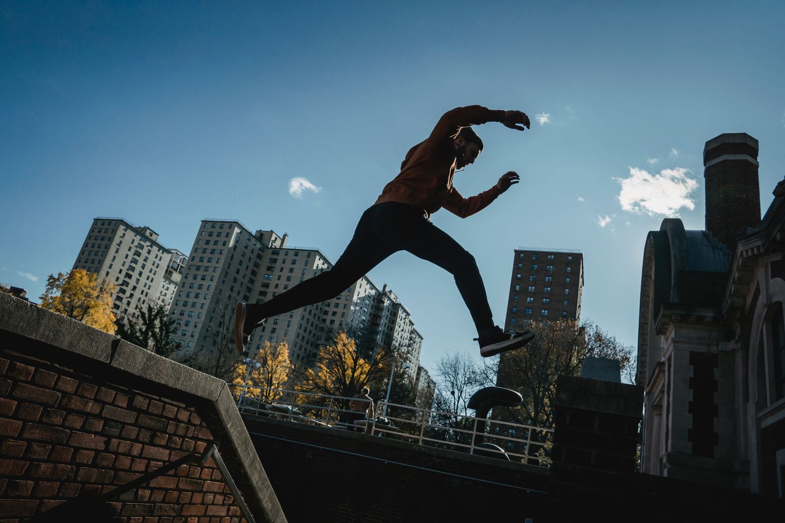 Parkour athlete leaping across a rooftop gap against a city skyline