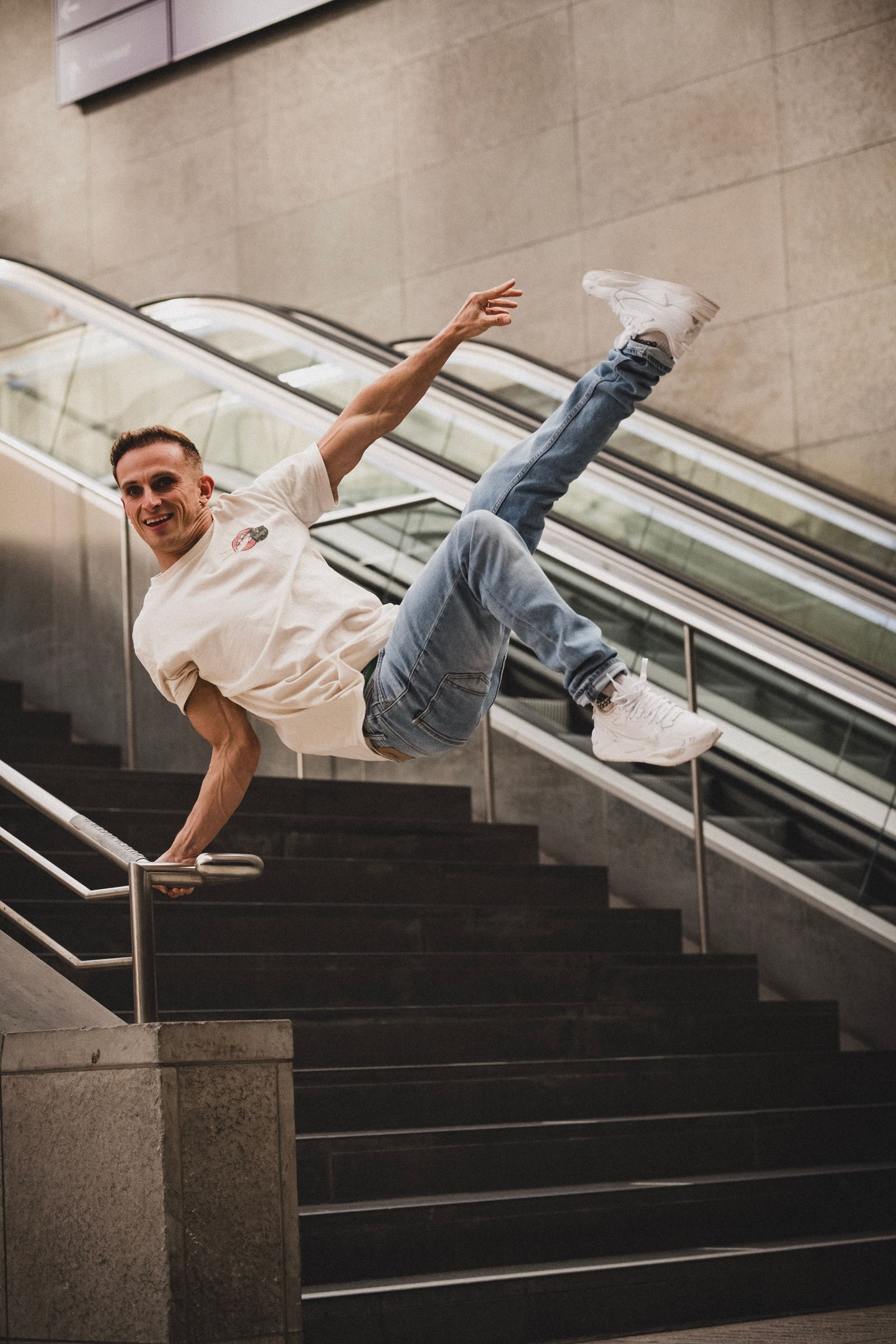 Tricking athlete balancing in a one-handed vault on a stair handrail in a transit station